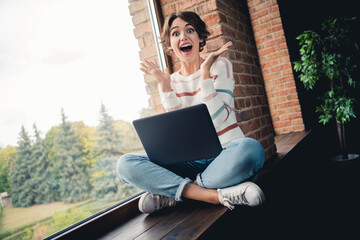 Full size portrait of astonished pretty girl sit wooden window sill open mouth use laptop online...