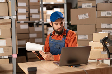 Small business aspiring entrepreneur working in warehouse using computer. SME e-commerce...