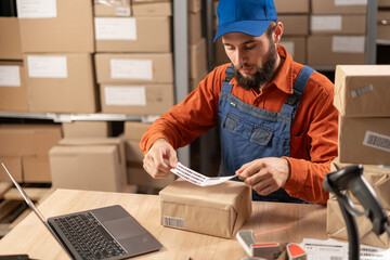 Online store owner sticking a barcode label at the package box and preparing an order for shipping...