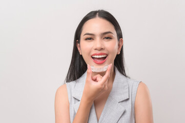 Young smiling woman holding invisalign braces in studio, dental healthcare and Orthodontic concept. - obrazy, fototapety, plakaty