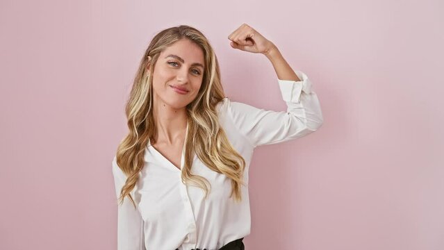 Confident, young, strong blonde woman showing off muscle power, wearing a shirt, stands with athletic pride over isolated pink background, embodying healthy lifestyle and fitness concept