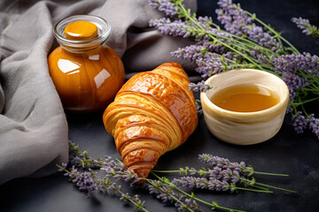 Croissant, honey and lavender on a black background.