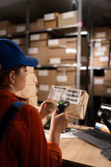 Warehouse worker scanning barcode on parcel using barcode scanner preparing parcels for shipment