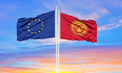 European Union and Kyrgyzstan two flags on flagpoles and blue cloudy sky . Diplomacy concept, international relations