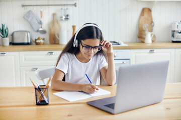Girl in headphones and eyeglasses e-learning at home
