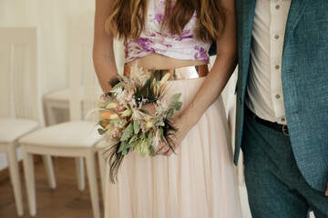 Eheschließung Braut hält modernen Brautstrauß mit Trockenblumen - 690253557