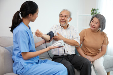 caregiver or nurse measure blood pressure to senior man on sofa