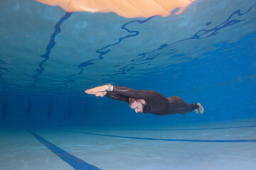 Side view of a young male practicing free diving at a public swimming pool
