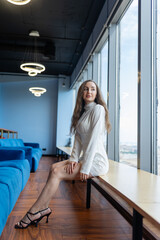 Executive manager enjoys spending coffee break looking out of panoramic window. Brunette CEO in...