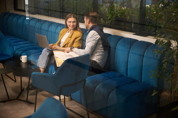 Female and male work with documents on soft blue sofa
