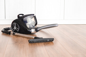 cleaning concept. Black vacuum cleaner stands on the floor in the apartment