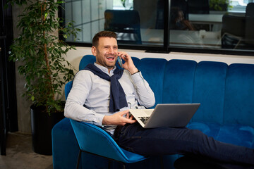 Manager with a laptop and mobile phone in coworking space