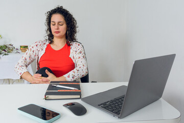 Young latin woman sitting in her Office Stretching her legs during break