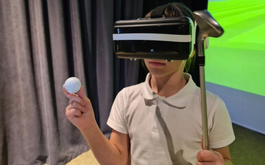 Teenage child golfer wearing virtual glasses holds golf club and ball