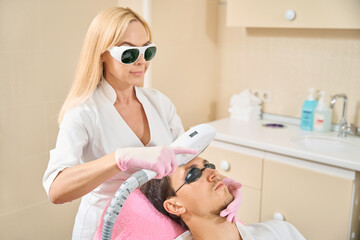 Cosmetologist conducts a session of hardware cosmetology to clinic client