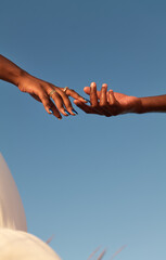 Crop black couple touching fingers in sunlight
