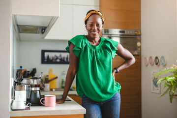 Portrait of a smiling mature woman standing in her kitchen 
