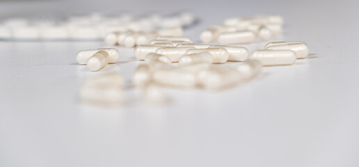 A lot of white capsules are scattered on the table. Drug concept, pharmacy. Place for text