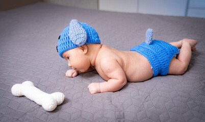 A baby laying on a bed next to a bone toy. A Baby Laying on a Bed Next to a Bone Toy