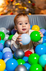 A baby in a ball pit surrounded by balloons. A Joyful Baby Surrounded by Colorful Balloons in a Ball Pit