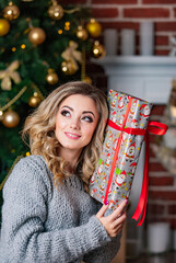 A woman holding a wrapped present in front of a christmas tree. A Woman Holding a Wrapped Present...