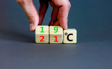 19 or 21 degrees Celsius symbol. Concept word 19 or 21 degrees Celsius on cubes. Beautiful grey background. Businessman hand. Lowering temperature to reduce energy consumption concept. Copy space.