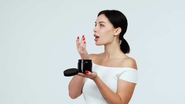 Portrait of a charismatic young woman using face creams. Concept of fresh moisturized skin, beautiful cosmetic face, happy healthy model. A young brunette takes care of her skin.
