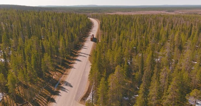 Aerial view of timber truck traveling along E75 road carrying logs at Tankavaara in spring, Sodankylä, Lapland, Finland.
