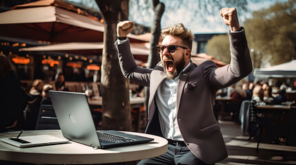 businessman is outside at a cafe, excitedly raising his fists in the air with a big smile, celebrating a win on his laptop - obrazy, fototapety, plakaty