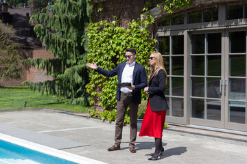 Blonde businesswoman explores available cottage residence from real estate agency. Woman listens to...