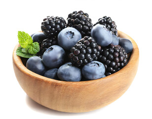 Wooden bowl with blueberries and blackberries isolated on white background