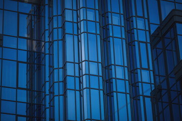 Windows of skyscraper with reflections on a background cloudy sky. The wall of the building is made of mirror glass. urban building design. Blue sky reflected in windows of modern office building
