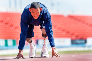 Front view of sport man athlete with a prosthesis on his leg action of start to run on the track at...