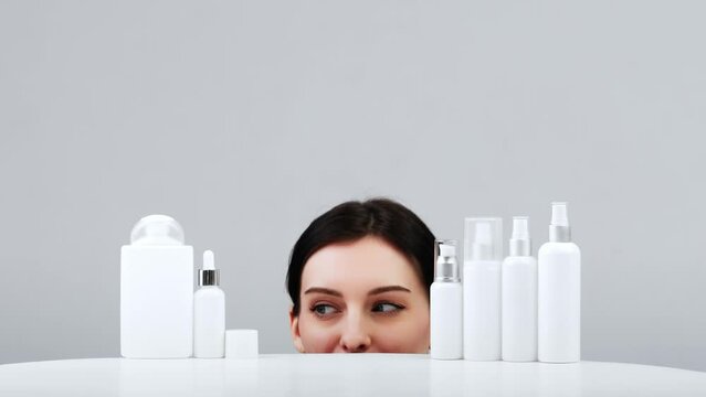 Cosmetics based on natural ingredients, scrub, toner. Production of natural cosmetics. A young woman on a light background of jars, bottles and tubes for cosmetic procedures.