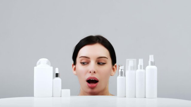 Cosmetics based on natural ingredients, scrub, tonic, body care. Production of natural cosmetics. Young woman on a light background among jars, bottles and tubes for cosmetic procedures on a white bac