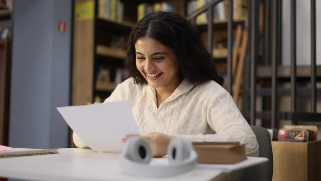 Portrait of happy student got an excellent grade mark for the test at university class Cute curly smiling girl looking at test in good mood indoors Exam passed Successful education concept