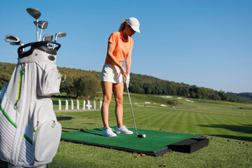Obraz premium Energetic Swing: A Young Golfer Tees Off with Style