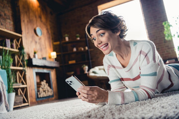 Profile portrait of cheerful overjoyed person lying carpet floor use smart phone chatting free time...