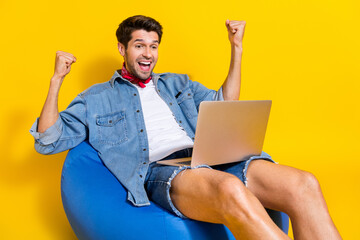 Full body photo of ecstatic man dressed denim shirt sit on bean bag with laptop win lottery yell...