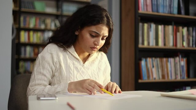 Portrait of worried young indian student working on difficult test which did not prepare at university class Upset girl feeling nervous during exams with hard program indoors