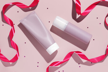 Blank pink plastic cosmetic tubes with pink ribbons. Cosmetic beauty product branding mockup. Copy space