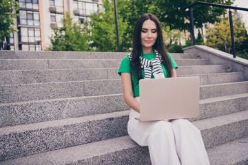 Photo of lovely cute woman dressed trendy clothes sitting on stairs in park working in park outside