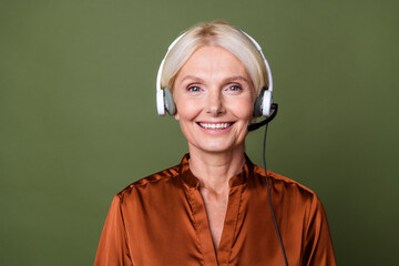 Photo of toothy beaming smart woman dressed silk shirt in headphones answer on customer questions...