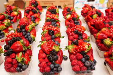 Venta de tarrinas de fruta en el mercado. - obrazy, fototapety, plakaty