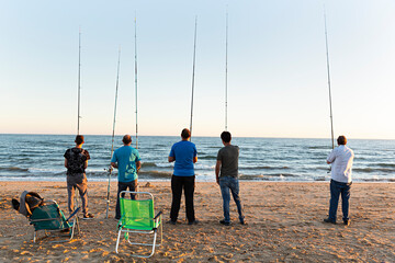 Grupo de pescadores pescando con la caña en la playa.