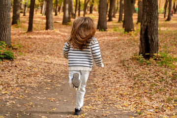 A beautiful teenage girl with long hair smiles and runs in an autumn park. Togliatti, Russia - 30 Sep 2023