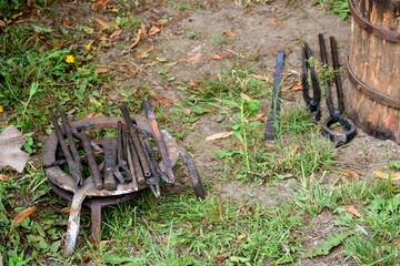 A close up on a set of equipment, tools, and ingredients used by a blacksmith, woodworker, archer, or cloth maker seen on a table located next to a tent on a sunny summer day