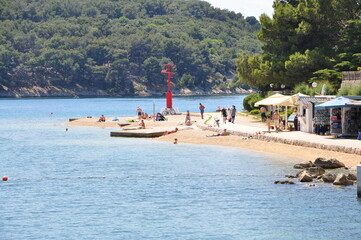 Red lighthouse of Cres (Croatia) on a sunny summer day. Summer vacation beach with people