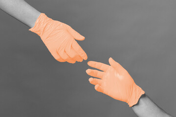Hands in medical gloves stretch to each other against gray background