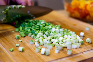 A woman cuts fresh spring onions on a cutting board. Cooking.